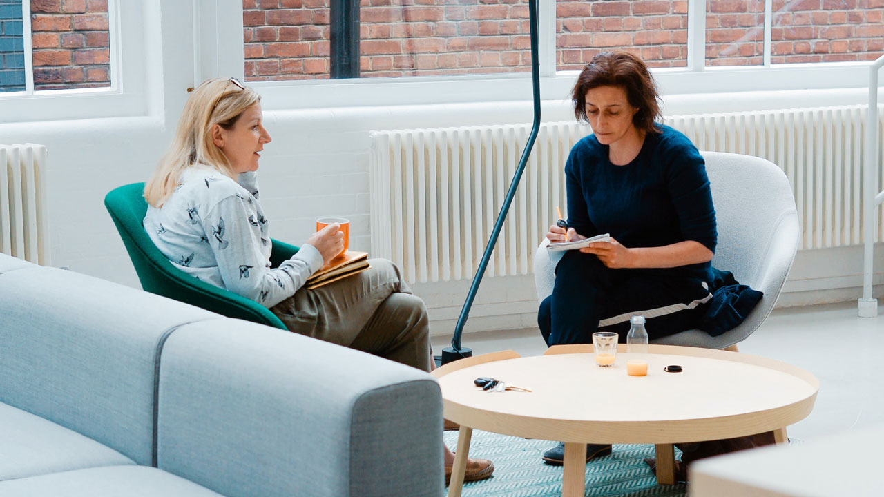 An image of two females sitting opposite each other, discussing an office space plan