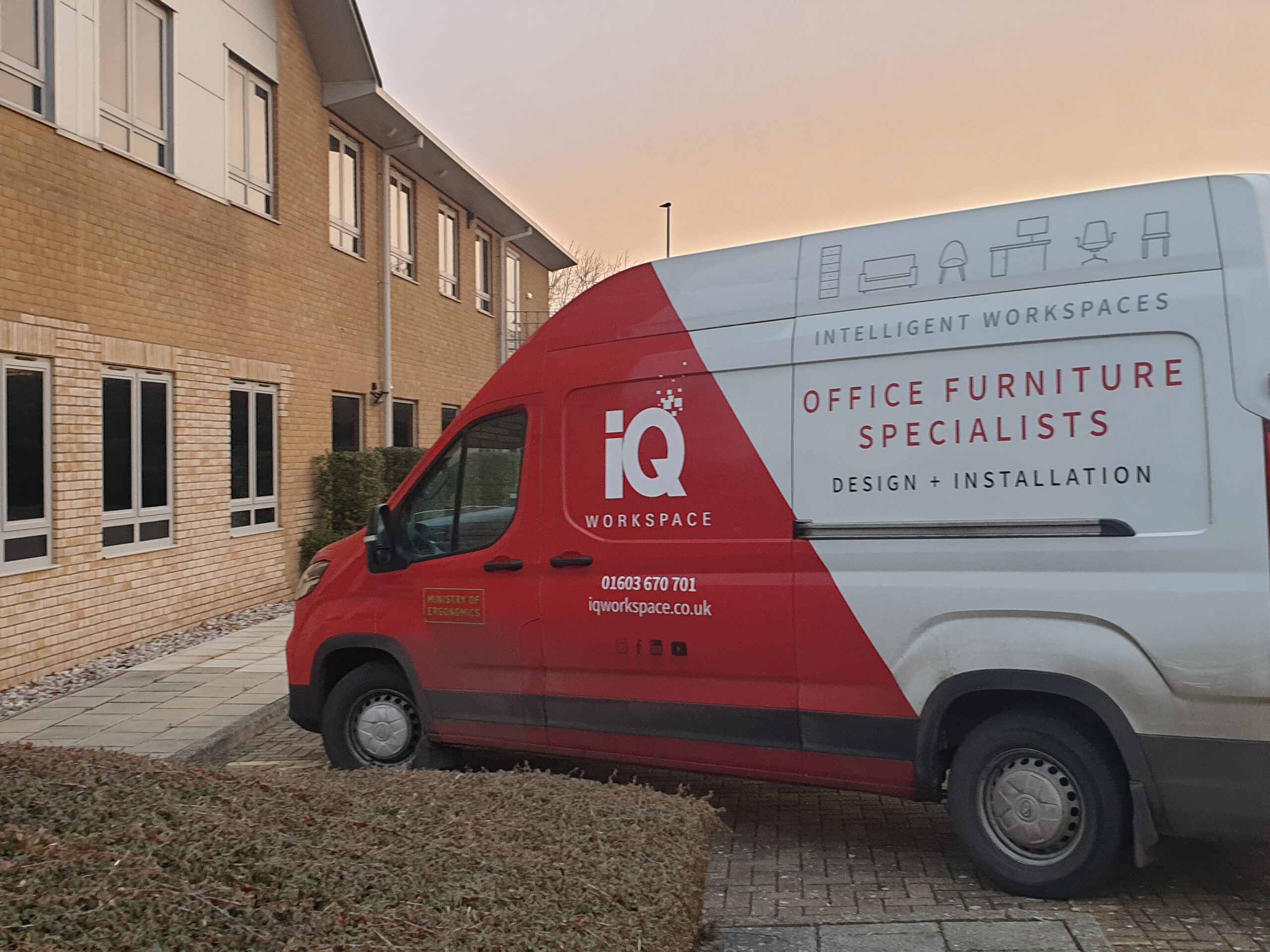An image of the iQ Workspace office furniture delivery van parked up. It is red and white.