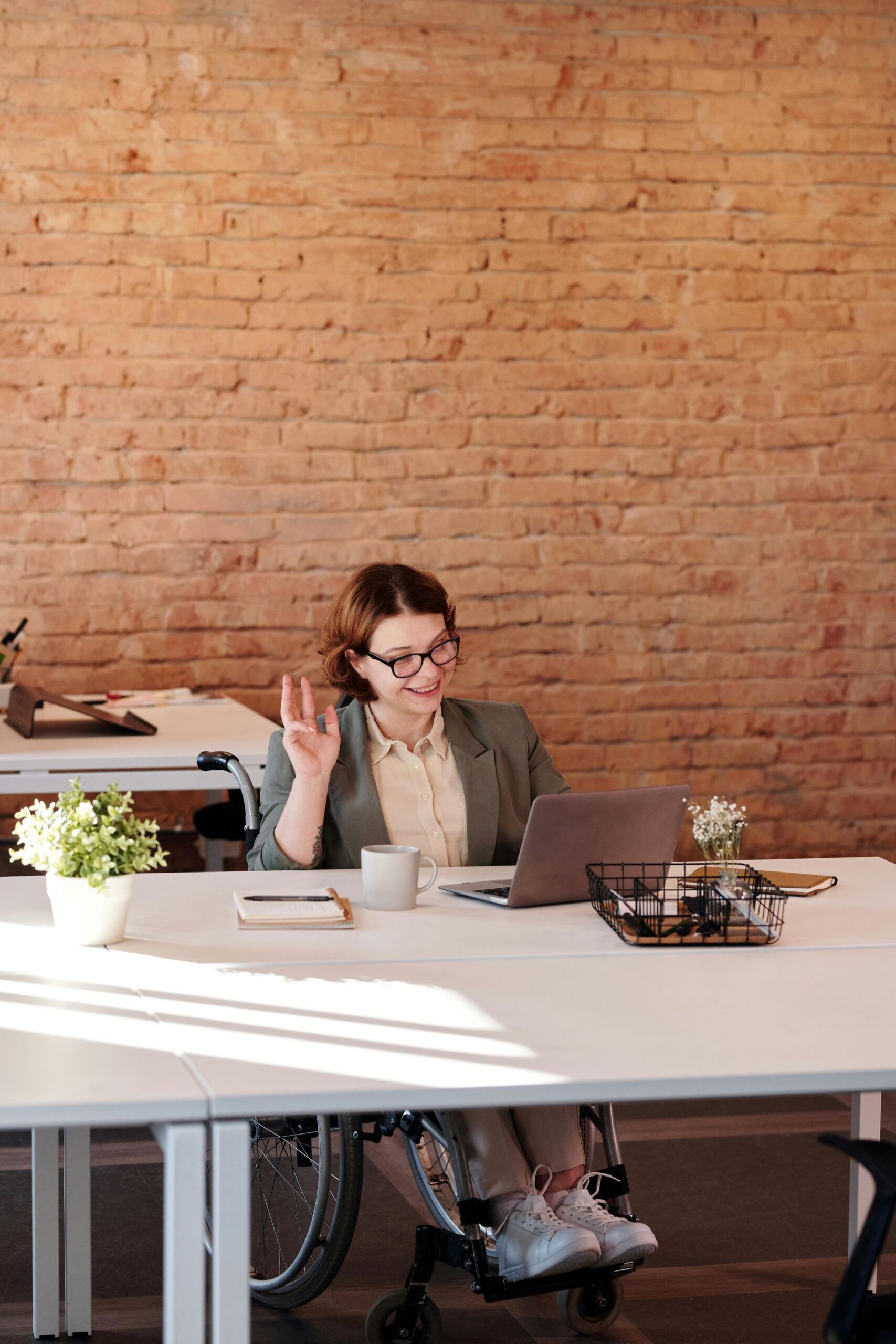 A lady in a wheelchair working on a laptop on a desk in the office