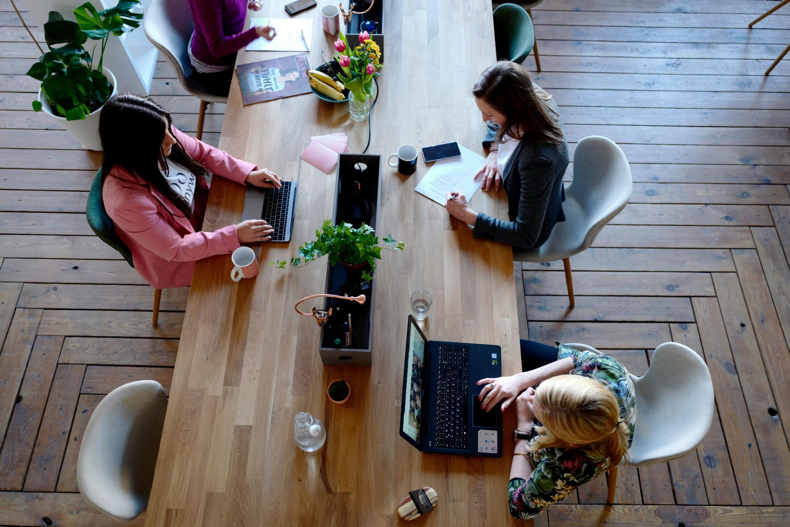 People working on laptops up a table in an office